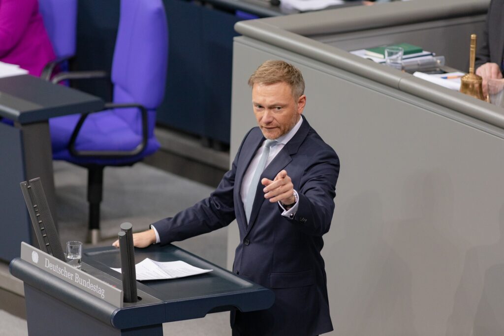 A person in a suit speaks and gestures passionately at a podium in the Deutscher Bundestag.
