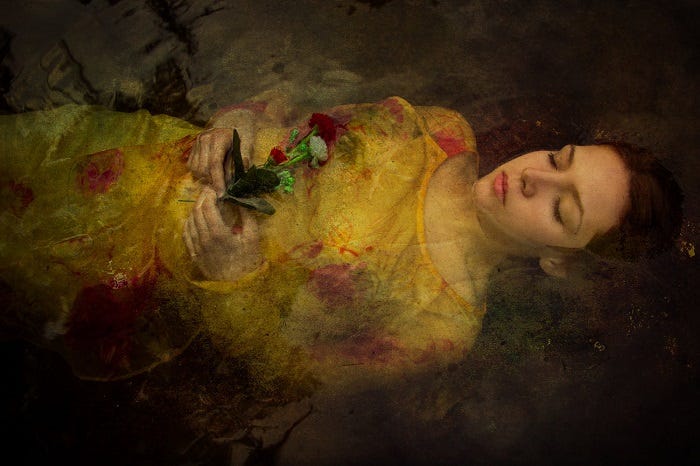 Woman in a yellow floral dress lying in water, holding a red rose, serene and dreamlike atmosphere.