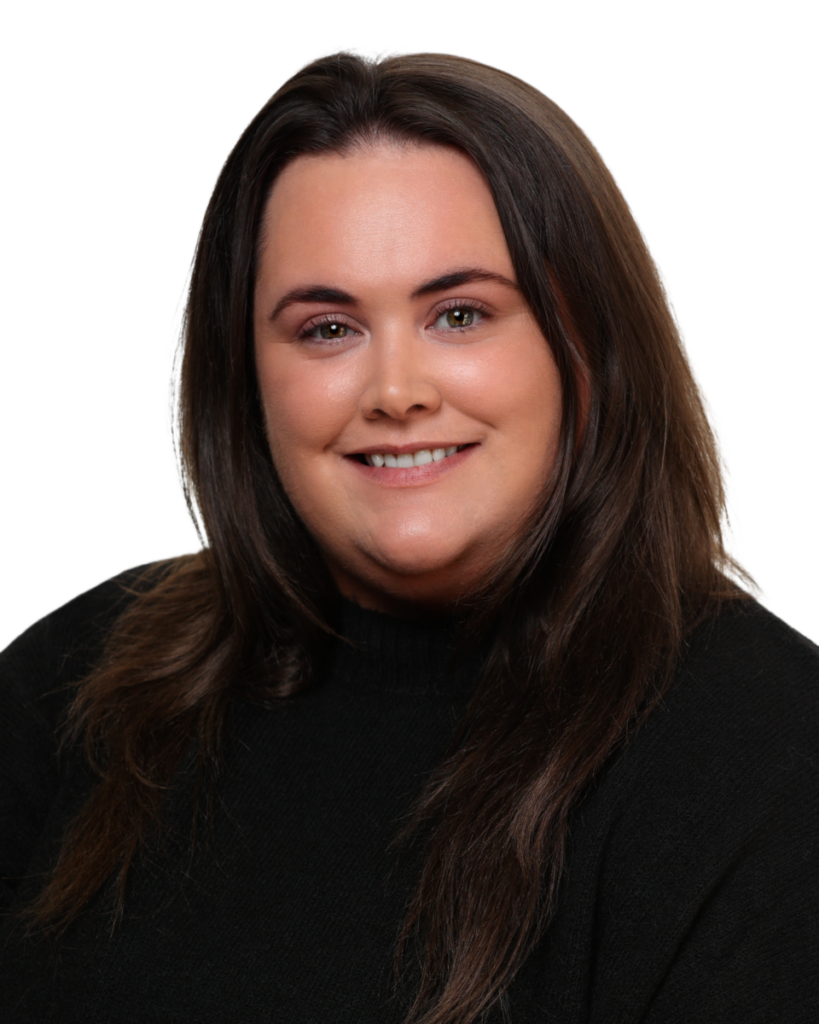 Portrait of a smiling person with long dark hair wearing a black top against a plain background.