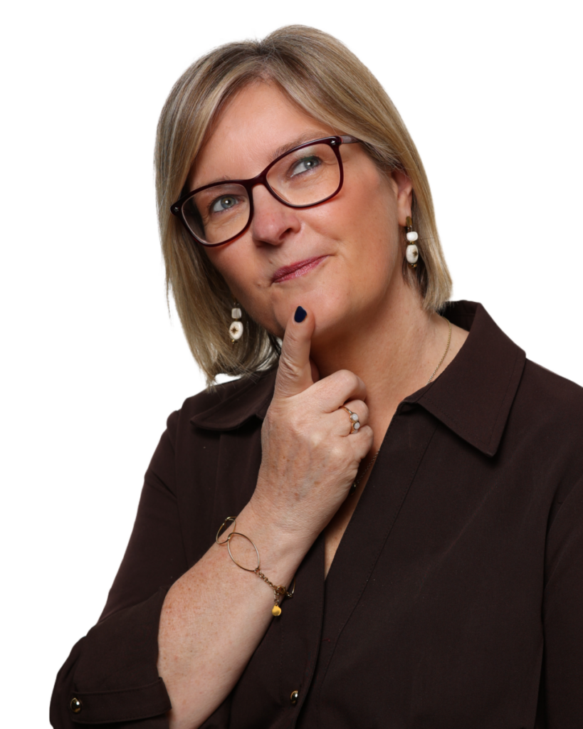 Woman in glasses with a thoughtful expression, touching her chin, wearing dark blouse and pearl earrings.