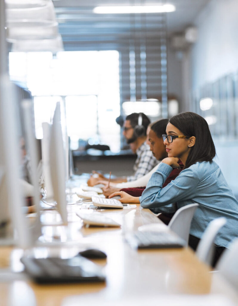 People working at computers in a modern office, focused and wearing casual attire.