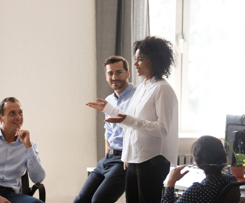 Diverse team in casual discussion around a bright office space, highlighting collaborative work and engagement.